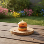 Pepper & White Happy Meal Freesia scented candle shaped like a cute burger with a smiling face on a wooden board.