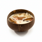 Pepper & White Coconut Grove candle in a natural coconut shell bowl with dried flower petals and a wooden wick