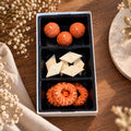 Pepper & White decorative wax candle set featuring orange textured spheres, white diamonds, and orange twisted rings.