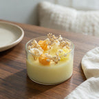 Pepper & White decorative glass jar candle with yellow wax roses and dried baby's breath on a wooden table.