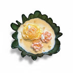 Pepper & White decorative soy wax candle in a forest green scalloped glass bowl with yellow and pink floral sculptures.