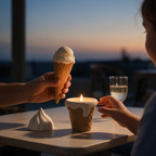 Pepper & White ice cream cone candle with dripping glaze on a table next to a real ice cream cone at sunset
