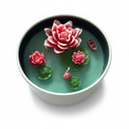 Pepper & White decorative lotus flower candle in a round bowl with pink wax blossoms and green lily pads.
