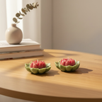 Pepper & White lotus flower shaped wax candles with red centers and sage-green petals on a wooden table