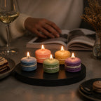 Pepper & White set of five colorful macaron shaped wax candles with lit wicks on a black tray for home decor