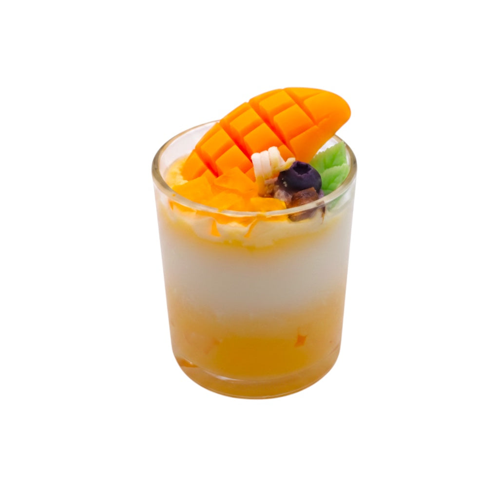 Pepper & White Tropical Delight mango scented dessert candle in a glass cup topped with fresh mango slices and fruit pieces
