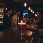 Pepper & White Scarlet Sip cranberry cocktail candle in a martini glass with a lit wick on a dark bar counter